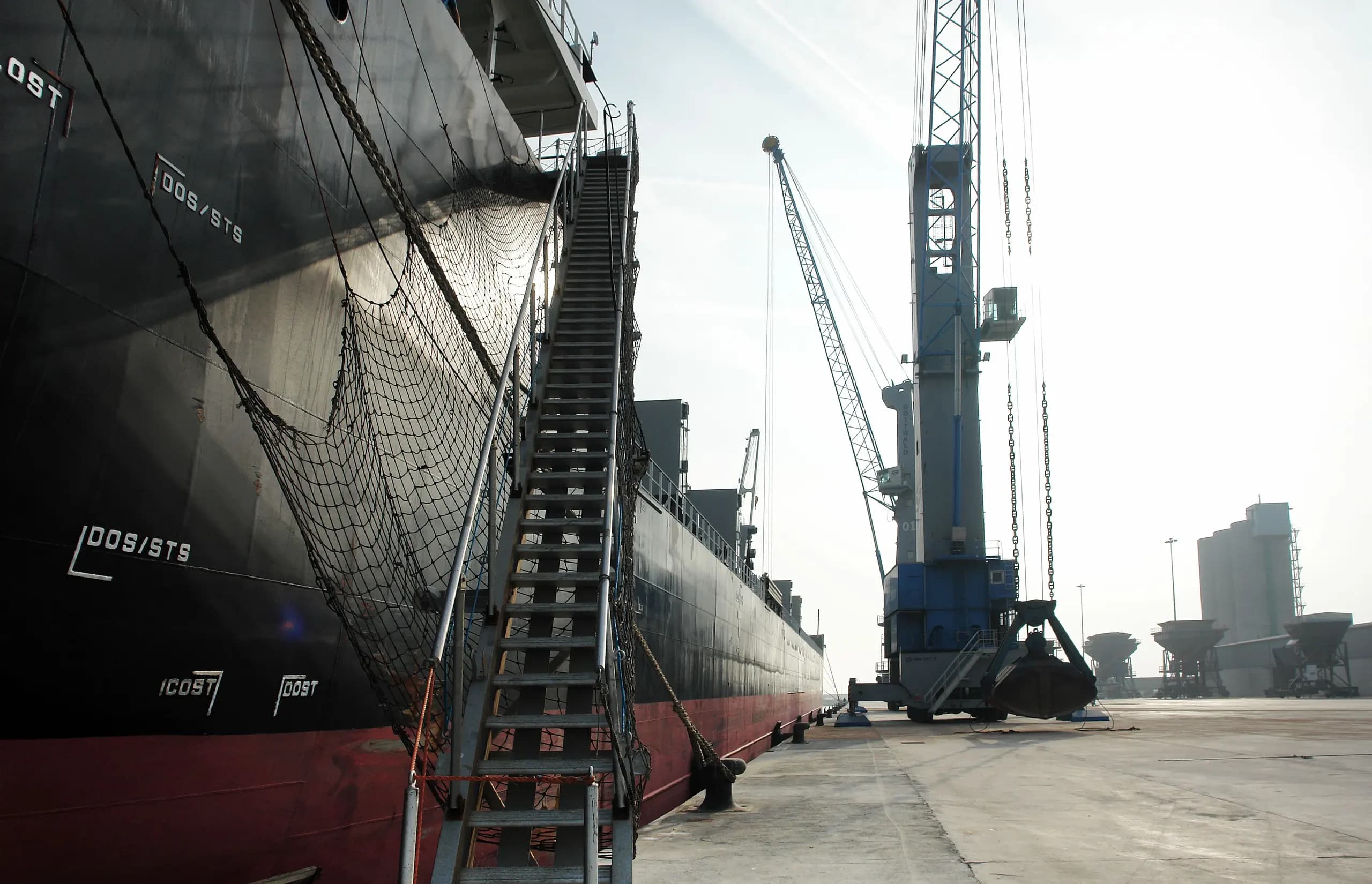 A cargo vessel alongside the quay with its gangway down and a crane working the berth